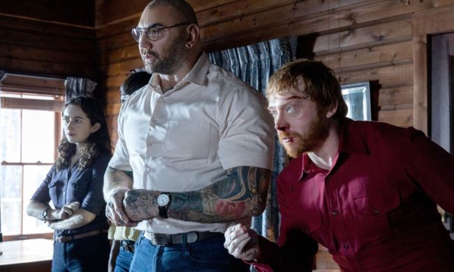 A woman and two men standing side by side and looking in the same direction in the movie Knock at the Cabin.